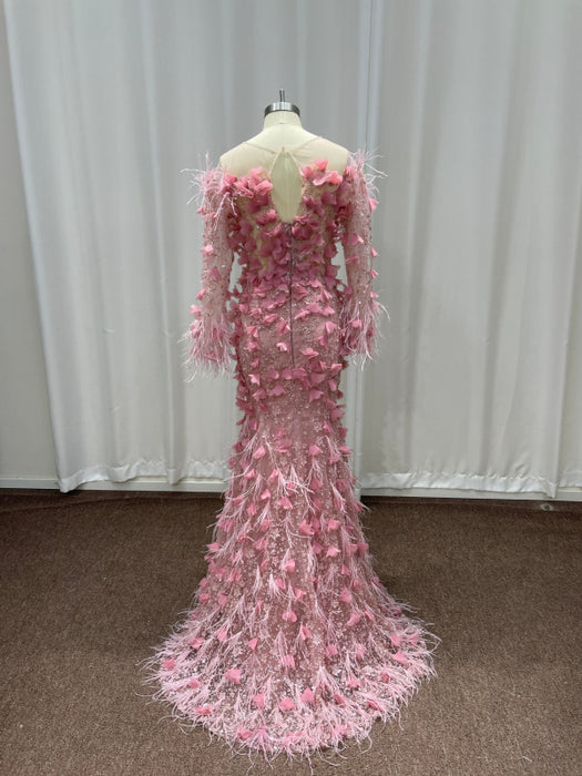 Pink evening gown with feathered details on a mannequin against a white curtain background.