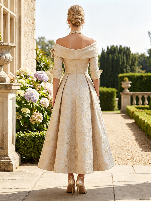 Back view of gold floral jacquard dress with bow shoulder