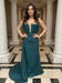 Woman in a green evening gown standing in a grand hallway with columns.