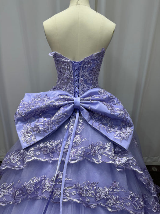 Purple ball gown with a large bow on a mannequin against a plain background