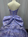 Purple ball gown with a large bow on a mannequin against a plain background