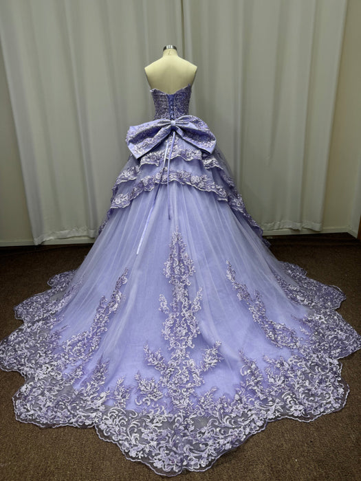 Lavender ball gown with intricate lace details on a mannequin against a plain background.